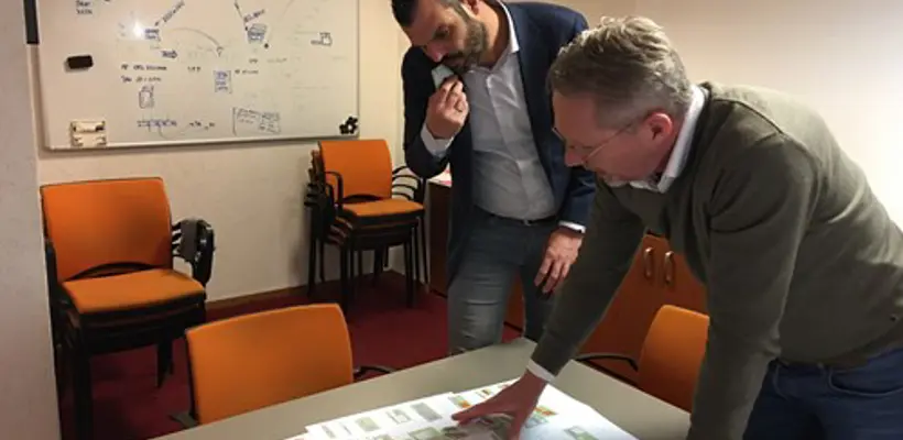 Een man die naar een papier op een tafel wijst