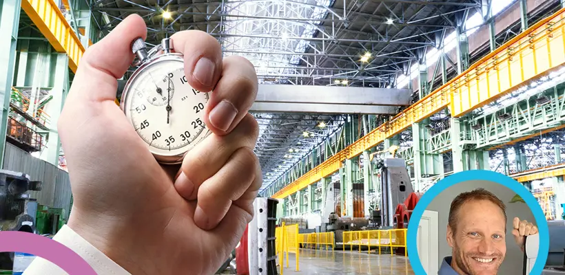 Een hand die een stopwatch vasthoudt in een fabriek