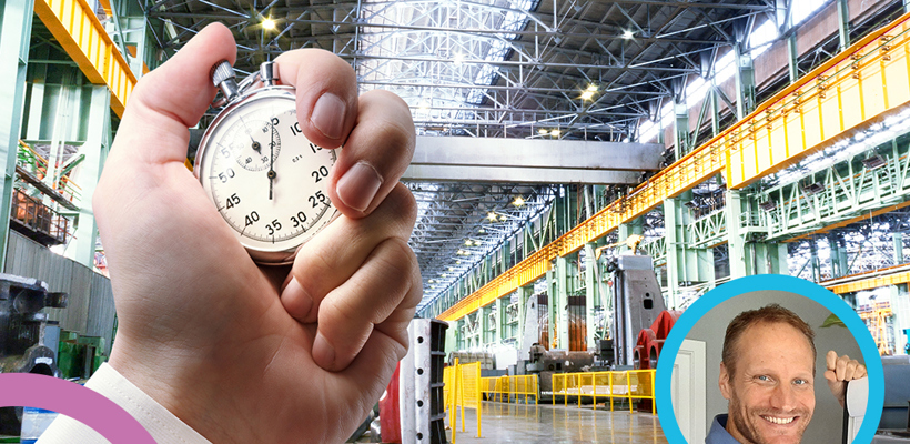 Een hand die een stopwatch vasthoudt in een fabriek