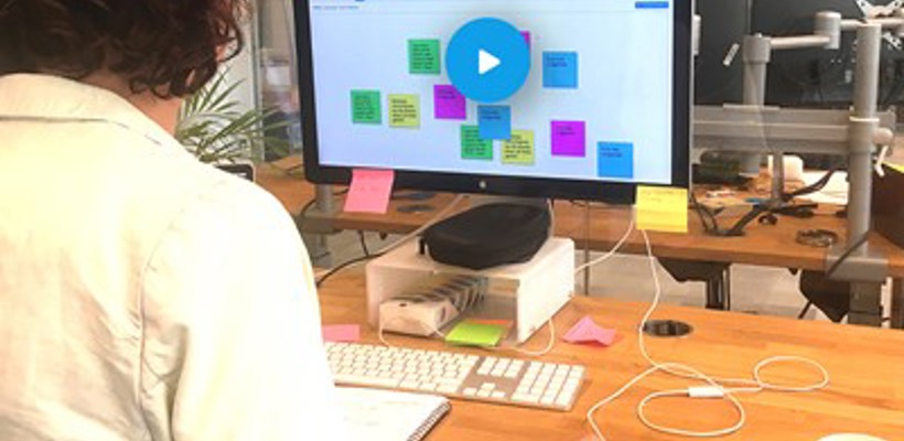 Iemand die aan een bureau zit en naar een computerscherm kijkt