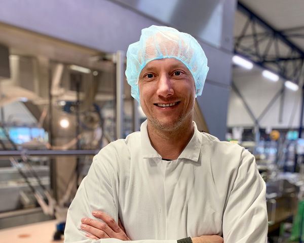 Een man in een witte jas en een blauw haarnet